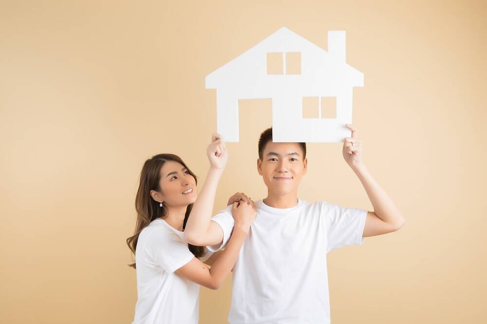 Young happy Asian couple presenting the symbols of house Young happy Asian couple presenting the symbols of house